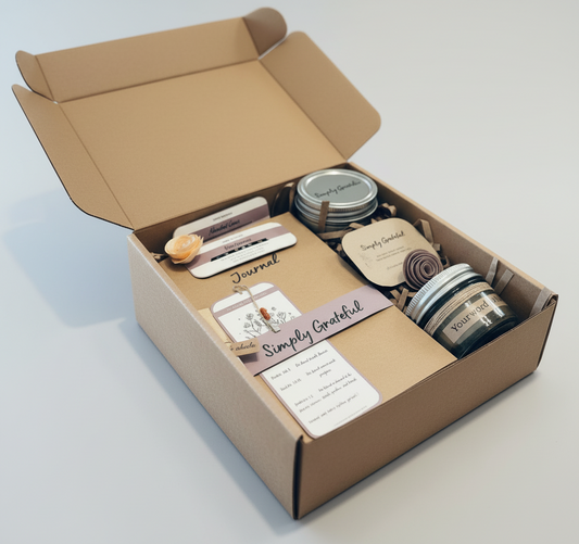 Open cardboard box containing various items including jars, a notebook, and a card on a light gray background.